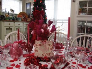 luxury-valentines-day-table-decoration_pink-angel-sculpture_red-candle_valentines-proverb_red-ribbon_glass-candle-holder_heart-shaped-ornament_pink-plate_romantic-ambiance_red-rose-petals-615×461
