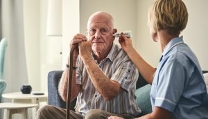 Healthcare worker checking senior man’s temperature